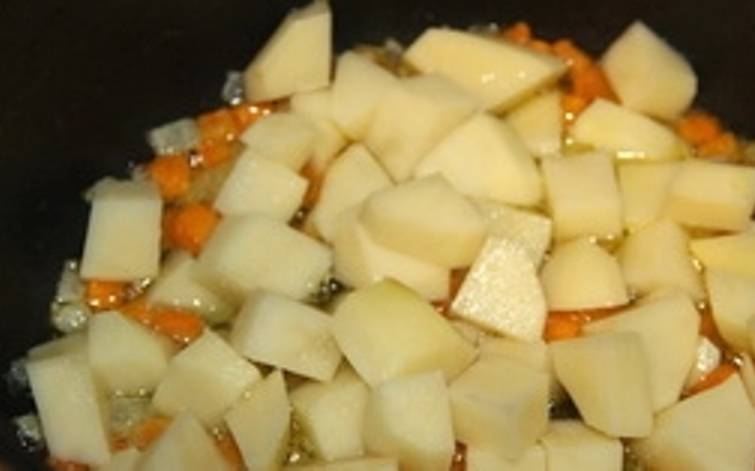 Очистите, порежьте картофель. Всыпьте его к морковке с луком и жарьте еще 3-4 минуты помешивая.