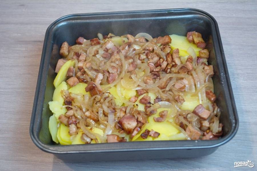 На картофель выложите обжаренные бекон с луком. Распределите равномерно.