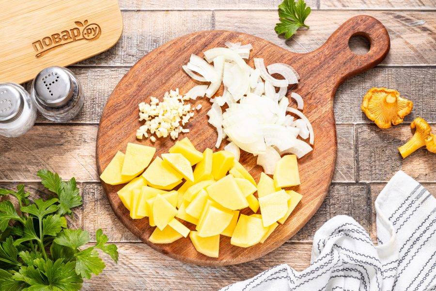 Картофель помойте, очистите и нарежьте на тонкие ломтики. Репчатый лук нарежьте полукольцами, а чеснок очистите и мелко порубите.