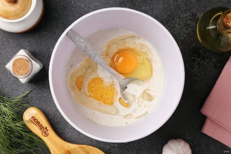 Добавьте соль, растительное масло и одно яйцо. Второе яйцо немного взбейте и отправьте в миску половину (второй половиной позже будете смазывать пампушки).