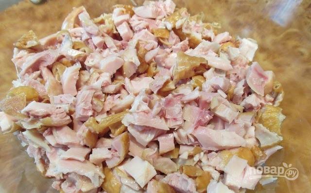 Копченые куриные бедрышки разделайте, отделите мясо от кости. Нарежьте курицу вместе с кожей на небольшие кусочки равного размера. 
