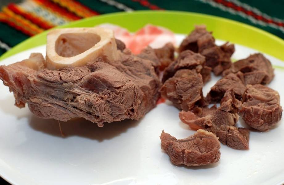 Когда мясо будет готово, внимаем его, отделяем от кости и нарезаем на небольшие кусочки, отправляем обратно в кастрюлю.