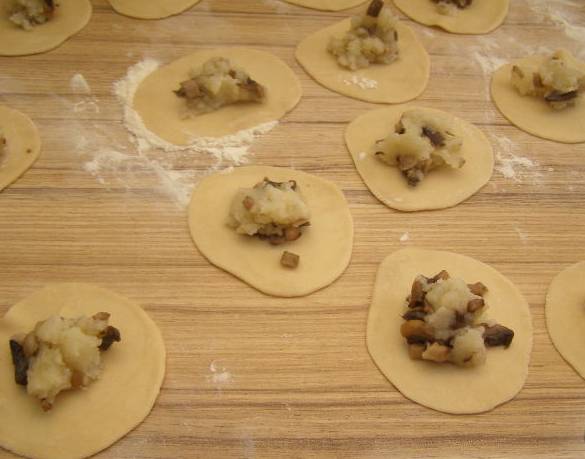 3. Теперь достаем тесто, раскатываем его в тонкий пласт, делим на кружочки. По центру каждого - начинка из картошки и грибов. Защипываем края и отвариваем в кипящей воде.