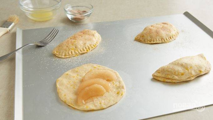 3.	Очистите яблоки от кожуры и нарежьте ломтиками, затем припустите на сковороде со сливочным маслом (1 столовая ложка) до мягкости. Выложите по 3-4 ломтика на каждый кружочек и посыпьте специями. Хорошенько закрепите края вилкой или вручную.