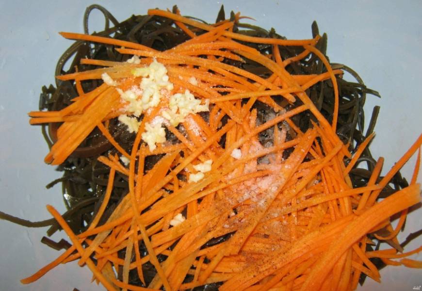 Морковку натираем на крупной терке соломкой. Добавляем в капусту. Затем посыпаем салатик сахаром, солью и специями по вкусу. Чеснок рубим мелко и добавляем в салат.