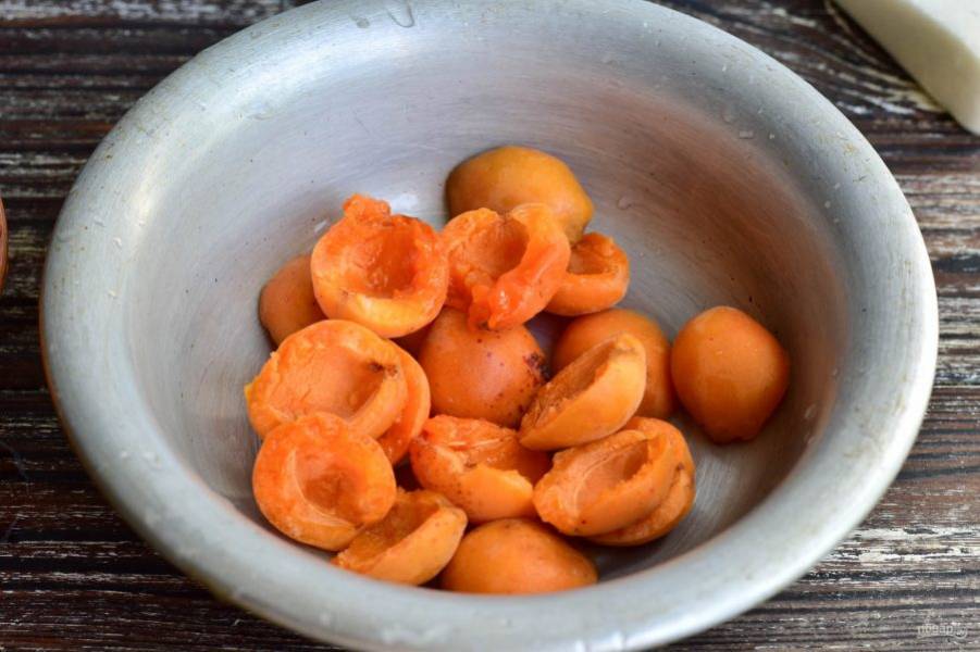 Вымойте абрикосы, разломайте каждый плод пополам, удалите косточки. Выложите часть фруктов в миску.