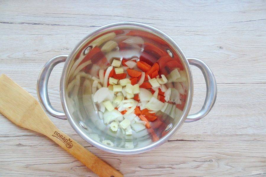 Стебель сельдерея вымойте, нарежьте кружками и добавьте в кастрюлю. Влейте подсолнечное масло и протушите овощи 5-7 минут.