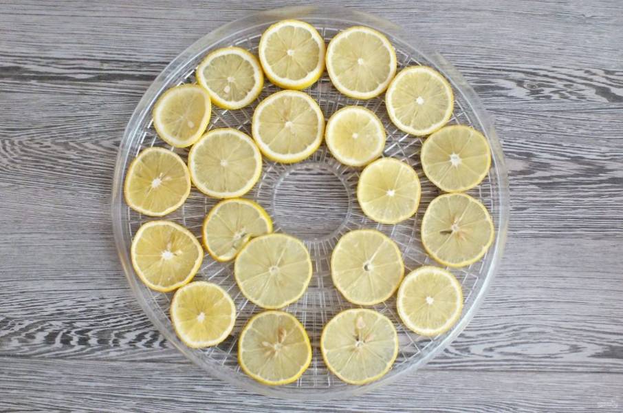 Разложите нарезанные лимоны на поддоны сушилки. Разложите "шайбочки" так, чтобы они минимально соприкасались друг с другом. Установите поддоны в сушилку, прикройте крышкой. Сушите при температуре 45-50 градусов от 7 до 9 часов.