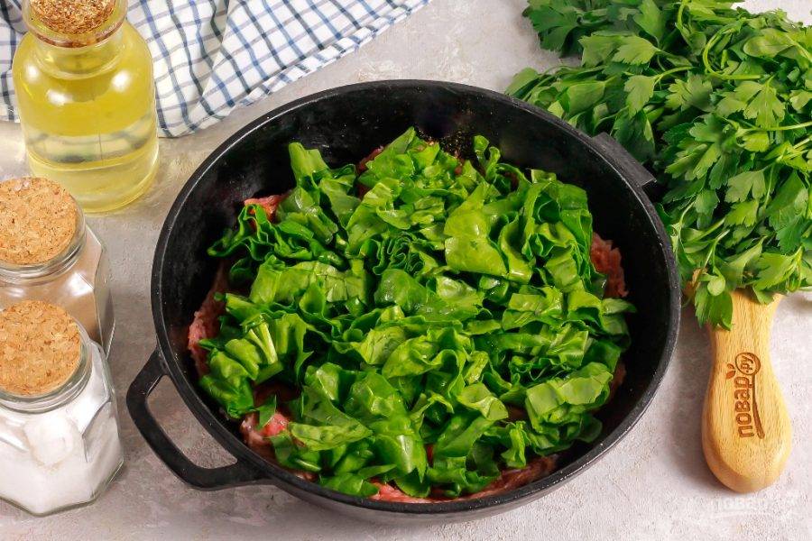 Промойте шпинат и стряхните с листьев лишнюю влагу. Нарежьте лентами и выложите на говядину.