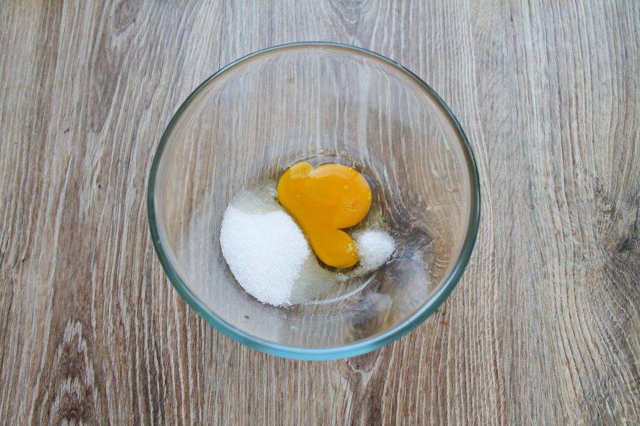 В миску разбейте яйцо, всыпьте сахар и соль. Взбейте все венчиком до однородности.