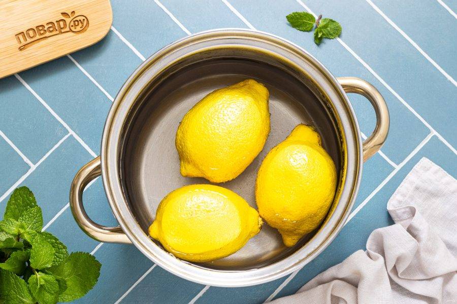 Лимоны опустите в горячую воду и проварите 2 минуты, так вы уберете лишнюю горечь из кожуры. После окуните их в холодную воду.