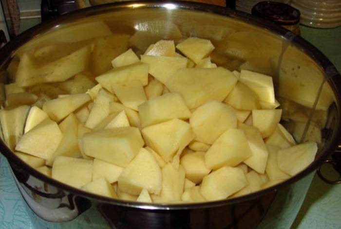 В большую кастрюлю выкладываем картошку, нарезанную кубиками, заливаем водой.