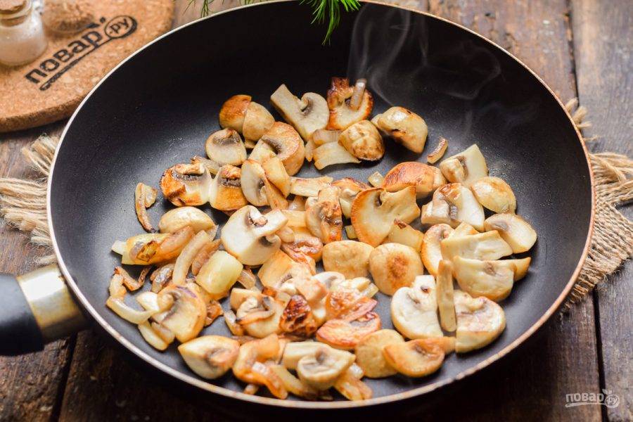 В сковороде прогрейте немного масла, выложите лук и грибы. Жарьте на среднем огне, помешивая, 4-5 минут до готовности.