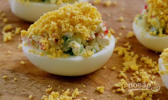 Начиняем белки крабовой начинкой, сверху посыпаем желтком. Яйца, фаршированные крабовыми палочками и огурцом, готовы, приятного аппетита!