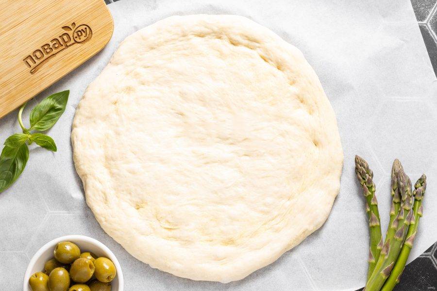 Выложите тесто на поверхность присыпанную манкой и аккуратно растяните. Придайте ему форму круга или овала, сформируйте бортики.