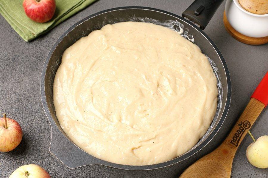 Вылейте на яблоки тесто и разровняйте его лопаткой.