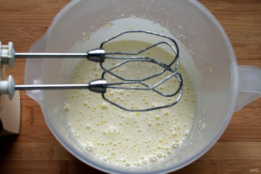 Отложите  столовую ложку сахара. Остальной сахар взбейте в пену с яйцами и натертой на мелкой терке лимонной цедрой половины лимона.