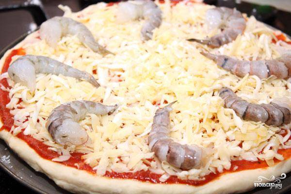 Раскладываем по поверхности пиццы ее начинку - креветки и каперсы. При желании можно добавить и другие любимые ингредиенты.