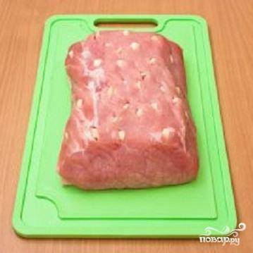 1. Кусок мяса хорошо промыть и обсушить. Зубчики чеснока нарезать на несколько частей. В куске мяса сделать надрезы и нашпиговать его кусочками чеснока.