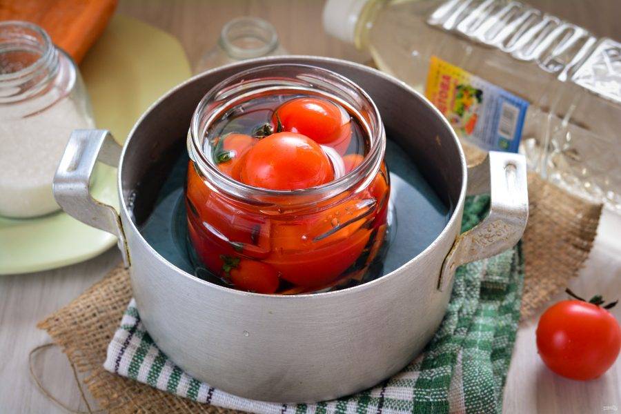 Залейте помидоры горячим маринадом и установите в кастрюлю с теплой водой. Под банку обязательно подложите ткань, чтобы стекло не треснуло.
