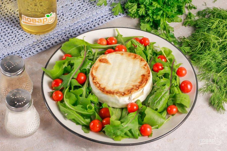 Выложите горячий сыр на листья рукколы в тарелке. Посолите и поперчите блюдо, сбрызните растительным маслом и сразу же подайте к столу.