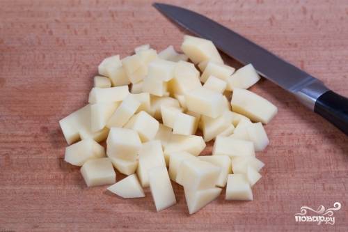 Картофель почистите, помойте, нарежьте кубиками. В кастрюлю влейте бульон без содержимого. Затем внесите картофель и кусочки отваренной курицы.