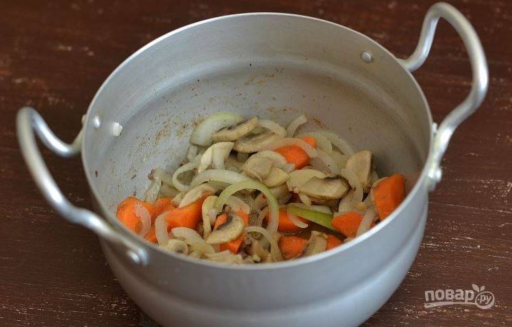 Замочите и почистите грибы. Нарежьте их пластинками. Затем очистите лук и морковь, вымойте их. Нарежьте овощи полукольцами. Припустите их в отдельной посуде вместе с грибами на растительном масле. 