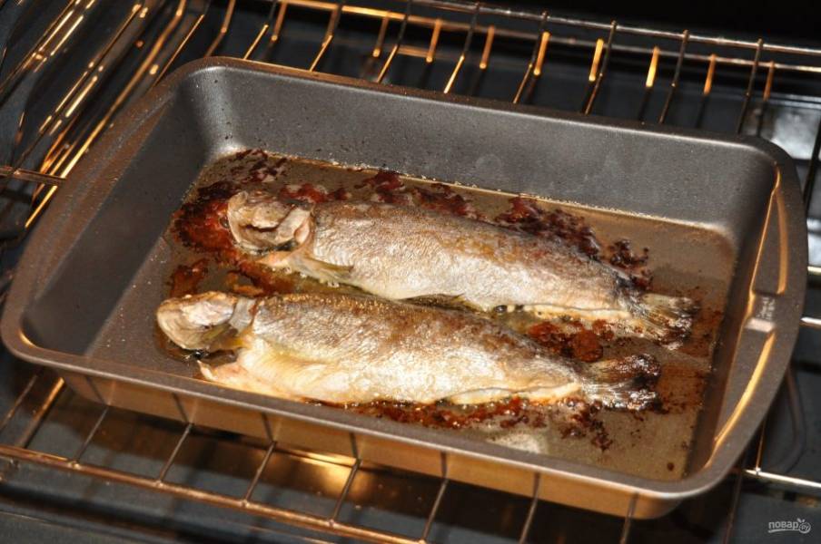 Запекайте рыбу в духовке 30 минут при 200 градусах. Через 20 минут после начала запекания смажьте форель растопленным маслом с противня. 