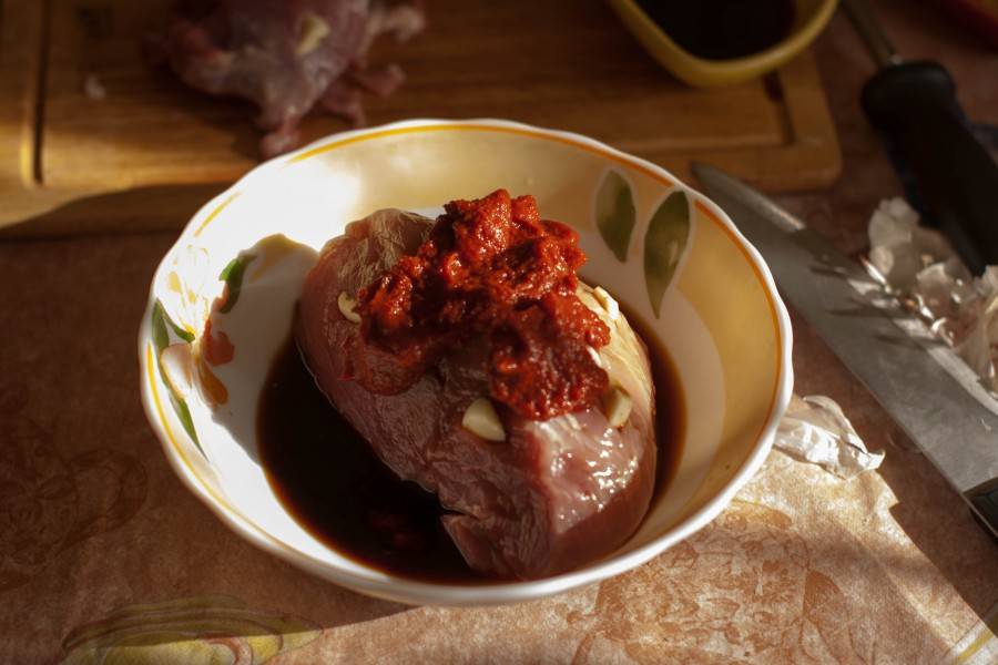 Затем замаринуйте мясо в соевом соусе, натрите томатной пастой. 