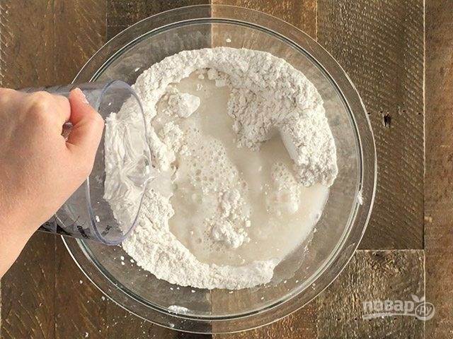 1.	В миску просейте пшеничную муку, добавьте к ней соль и дрожжи. Влейте стакан теплой воды.