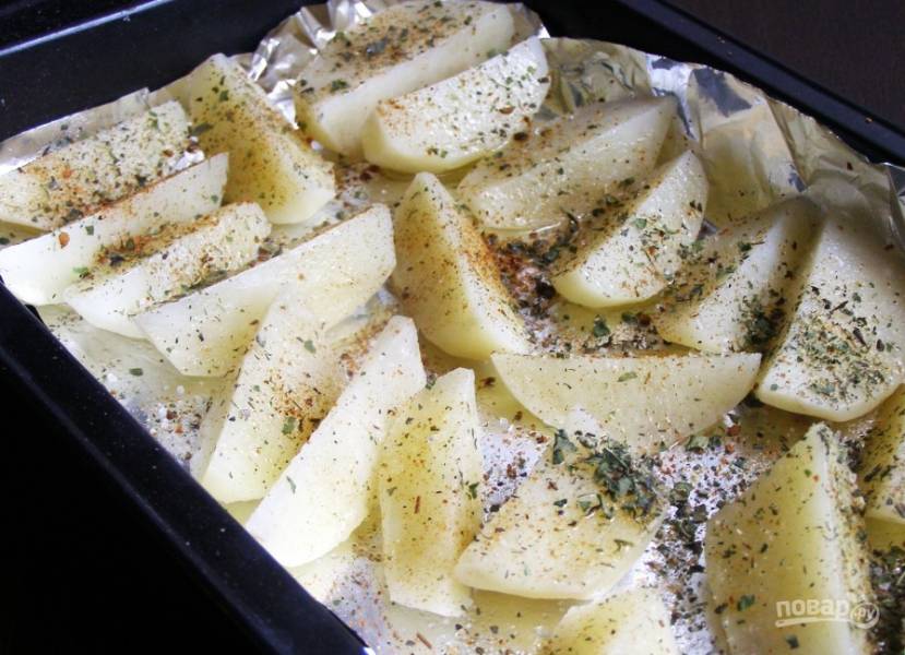 Потом отправьте картофель на противень, застланный фольгой. Промажьте его маслом и специями. Запекайте гарнир в духовке при 190 градусах в течение 25 минут.