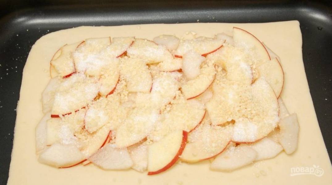 Целый пласт теста выложите на противень. Сверху распределите яблоки и груши. Присыпьте начинку миндалём и сахаром.