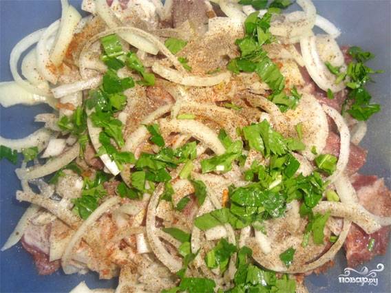 Мясо укладываем в удобную посуду, к нему высыпаем полукольцами нарезанный лук. Хорошо солим, перчим, добавляем специи по вкусу и мелко нарубленную зелень.