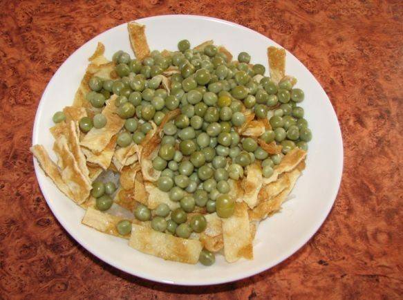 5. У меня куриное мясо было уже отварное. Лучше брать филе, но бедра или другие части тушки также подойдут. Филе варится не более 25 минут, поэтому это можно сделать и в процессе приготовления салата. К омлету добавляем нарезанное куриное мясо и горошек.
