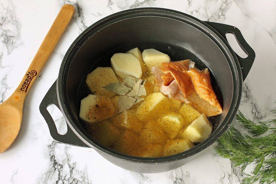 Добавьте к картофелю специи, лавровый лист и копченую куриную кожу (для аппетитного аромата). Залейте картофель водой, чтобы она почти полностью покрывала его и поставьте тушиться на средний огонь.