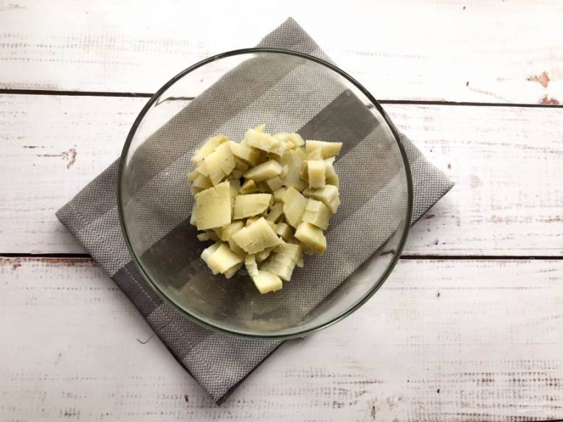 Вареный картофель очистите от кожуры, нарежьте небольшими кубиками и выложите в глубокую тарелку. 