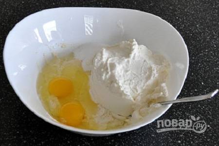 2. В глубокую мисочку отправьте яйца. Туда же выложите нежирный творог. Тщательно взбейте все до однородности. 