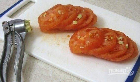 С ошпаренных помидоров снимите кожу. Затем нарежьте их кружками. Смажьте их чесноком, пропущенным через чеснокодавку.