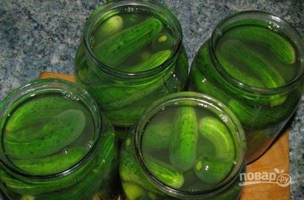4. На дно баночки выложите немного укропа, чеснок и перец. Всыпьте сахар, соль и влейте уксус. Выложите огурчики. Залейте их чистой холодной водой.