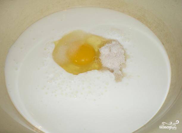 На дно большой миски выливаем холодный кефир. Туже же разбиваем яйцо, добавляем соль и сахар. Хорошенько взбиваем массу миксером.