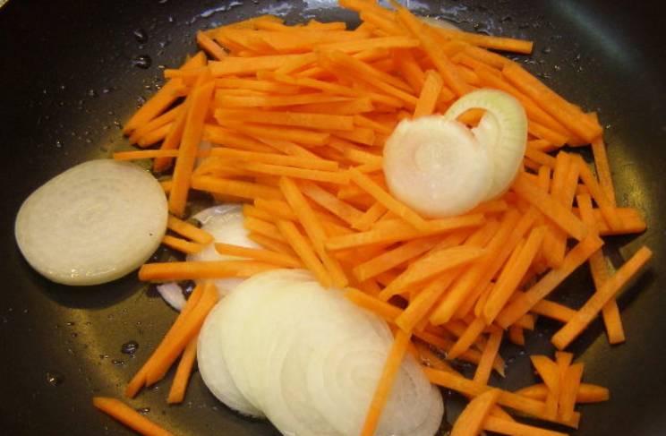 Разогреваем в сковороде растительное масло, и обжариваем на нем лук с морковью. Готовим 10 минут, помешивая.