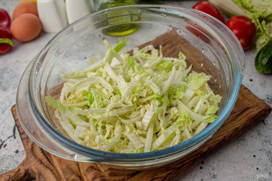 Пекинскую капусту тонко нашинкуйте, используйте только верхние, тонкие листья. 
Выложите нашинкованную капусту в салатник.