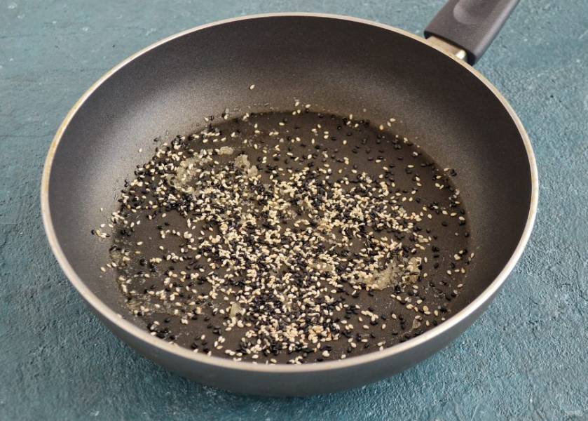 Нагрейте в сковороде до средней температуры растительное масло. Добавьте семена кунжута и жарьте, помешивая, до золотистого цвета, в течение 5 минут. 