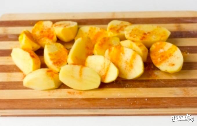 Чистим картофель и нарезаем его дольками. Присыпаем картошку куркумой и красной молотой паприкой.