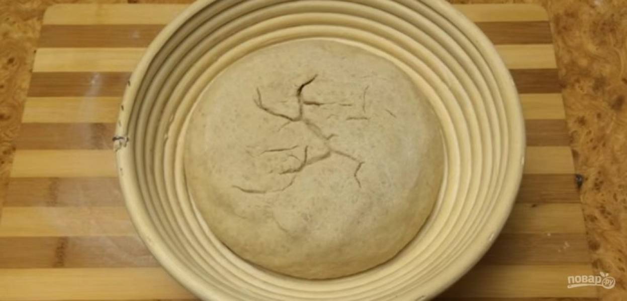 6.  Накройте миску пленкой и оставьте на 1-2 часа при комнатной температуре. Аккуратно переложите хлеб на пергамент. Стряхните лишнюю муку, сделайте несколько надсечек крест-накрест, сбрызните хлеб водой. 