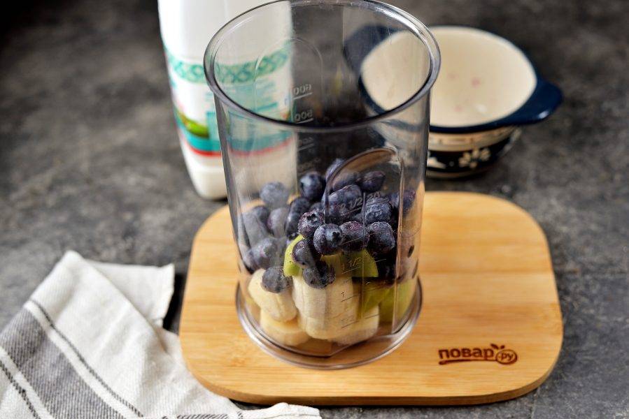 Переложите киви с бананом в чашу блендера, всыпьте ягоды черники или голубики.