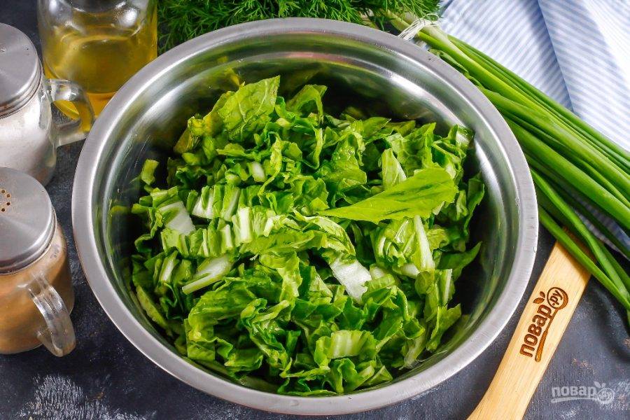 С пекинской капусты снимите верхние листья. Нарежьте зеленую часть овоща и выложите ее в глубокую емкость.
