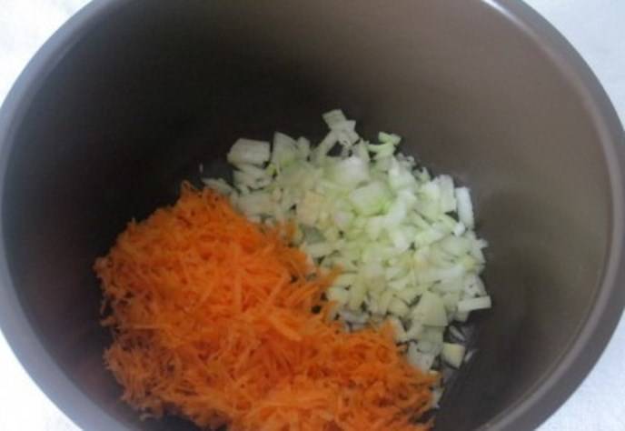 Морковь потрите на крупной терке. Лук порежьте мелкими кубиками. Сложите их в чашу мультиварки и добавьте растительное масло. 