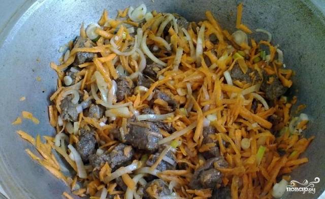 Нарезаем лук полукольцами, а морковь трем на крупной терке или нарезаем соломкой. Выкладываем их в казан к мясу и все вместе обжариваем несколько минут.