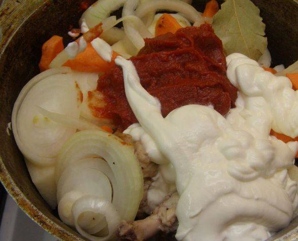 3. Перекладываем в казан мясо с остатками масла, подготовленные овощи, сметану и томатную пасту. Заливаем водой и ставим на огонь.